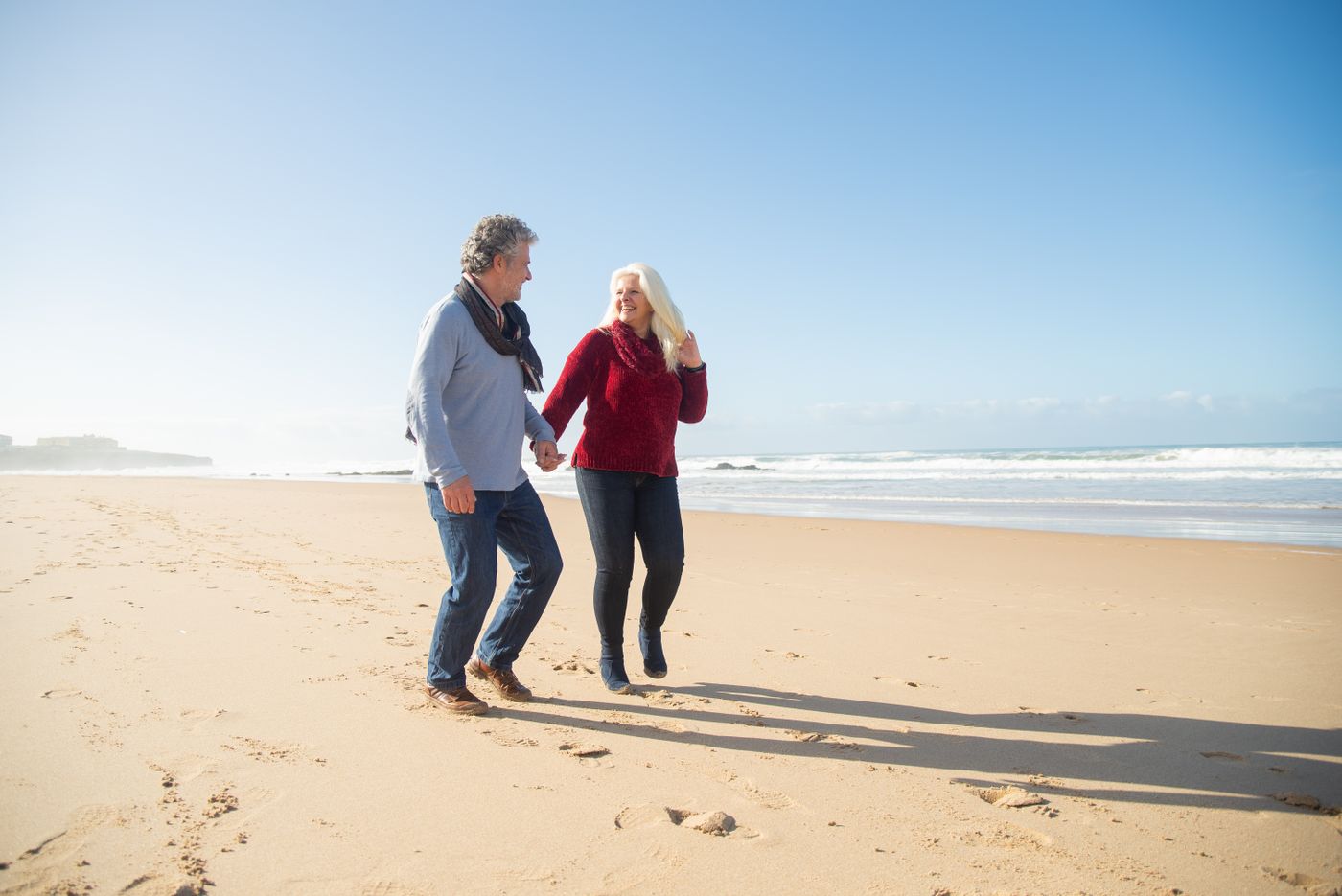 An older couple walking together along the beach near Naples
